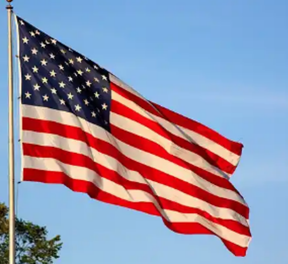 A flag flying in the wind on top of a pole.