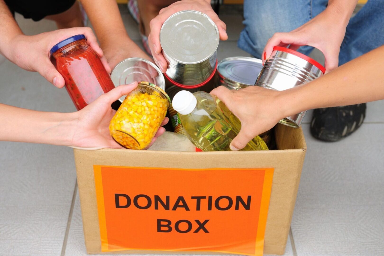 A box of food that is being filled with cans.