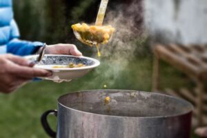 A person is cooking food in an outdoor kitchen.