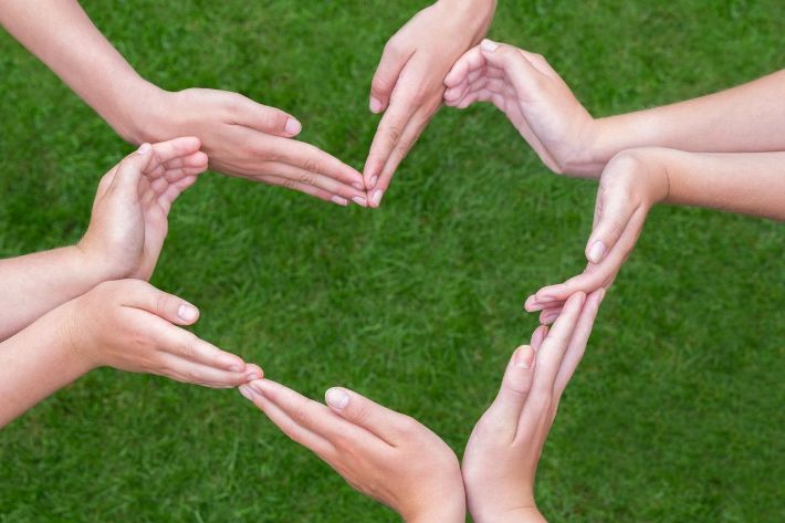 A group of hands forming the shape of a heart.