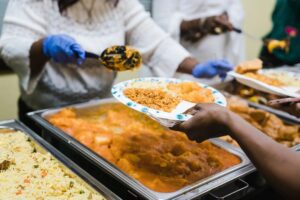 A person holding food in their hand while another holds a plate.