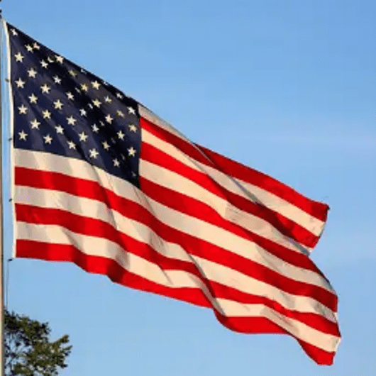 A flag flying in the wind on top of a pole.